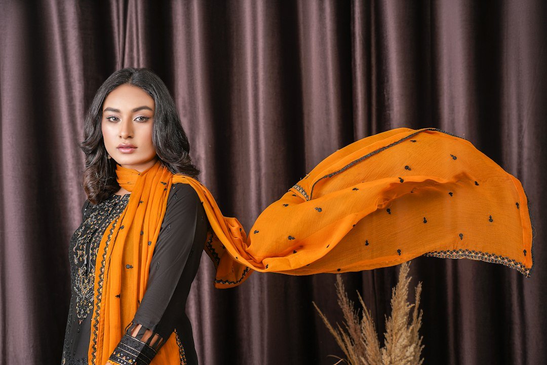 a woman in a black and orange outfit with a yellow scarf