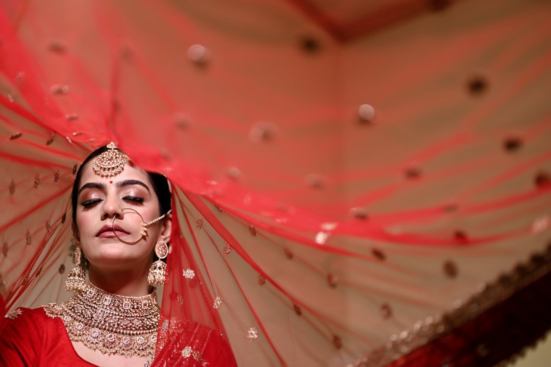 a woman in a red outfit with a veil over her head