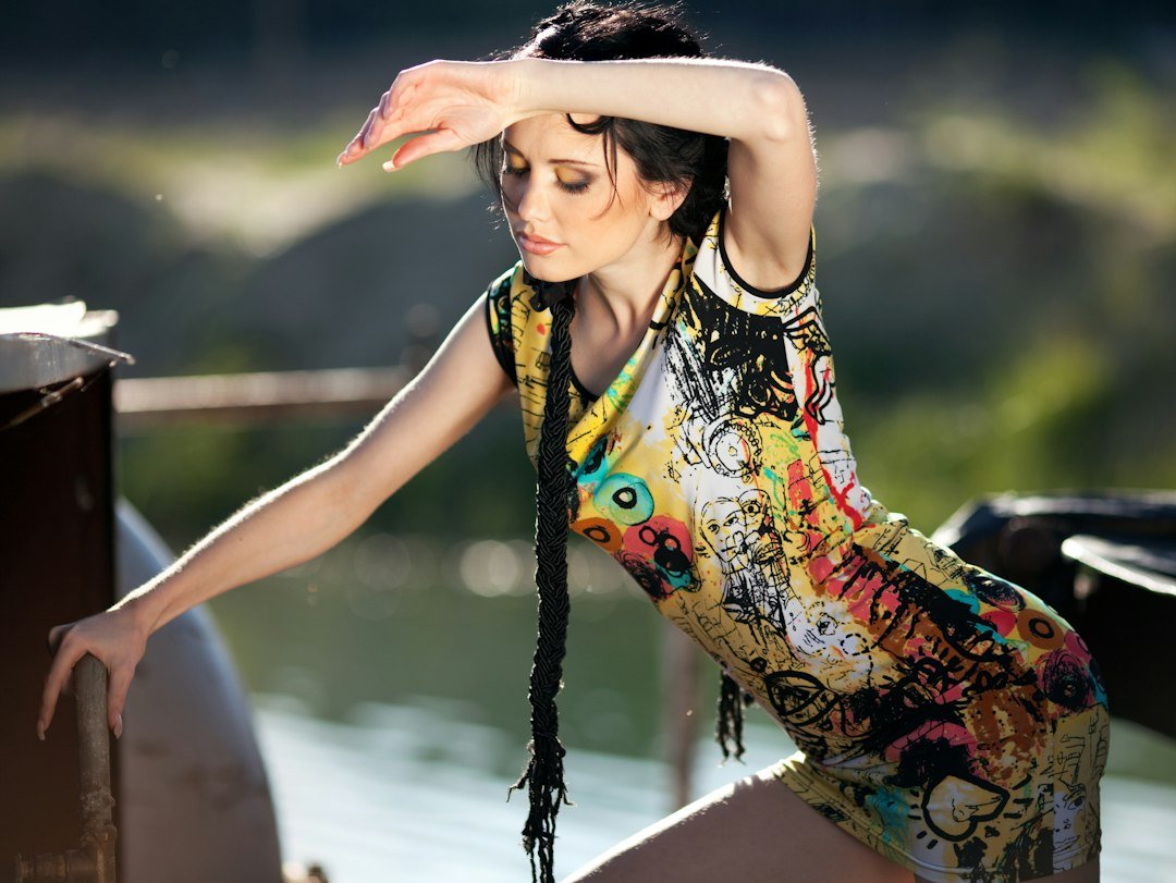 A woman in a colorful dress shields her eyes outdoors