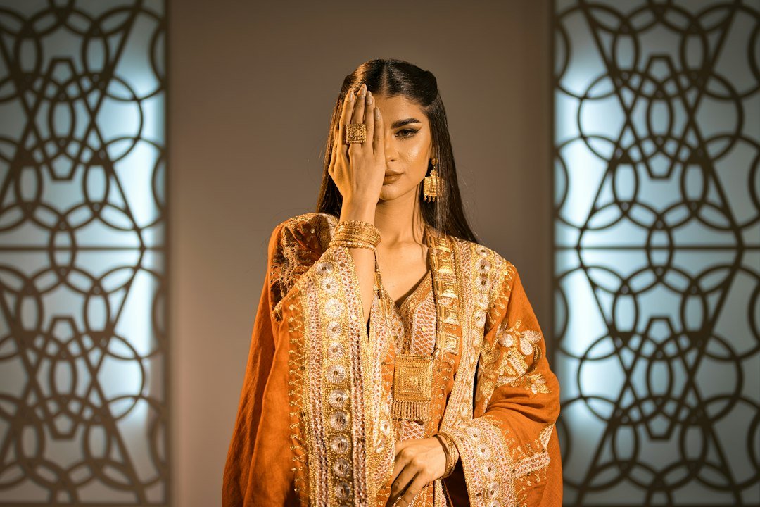 Woman in ornate clothing covering one eye